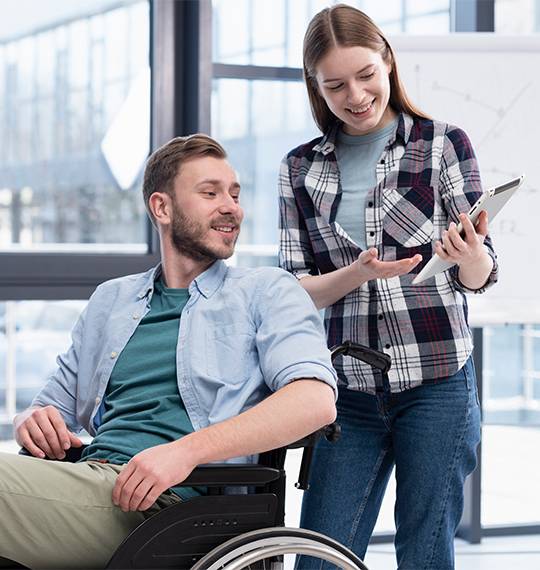 A caregiver supporting a man in a wheelchair with a clipboard, representing disability support services Melbourne