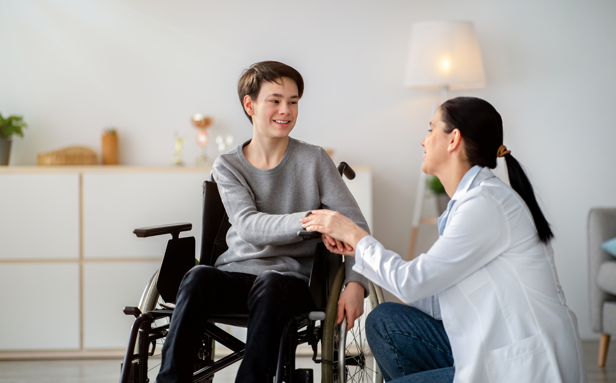Caregiver playing guitar with a person in a wheelchair in a supportive home environment, Melbourne disability services