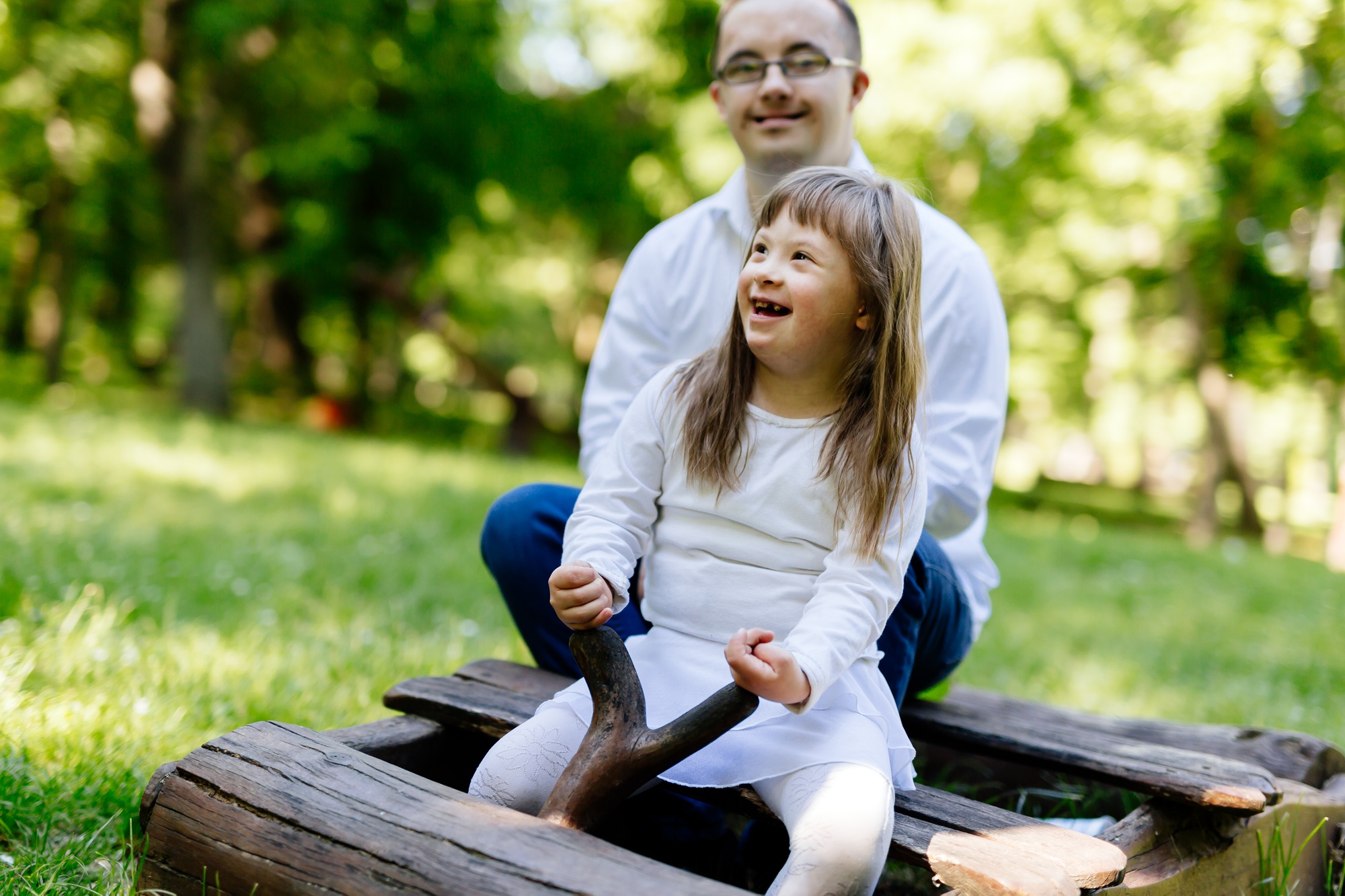 A man and young girl with Down syndrome playing outdoors, joined by an elderly woman in a wheelchair and a caregiver, showcasing NDIS disability services Melbourne.