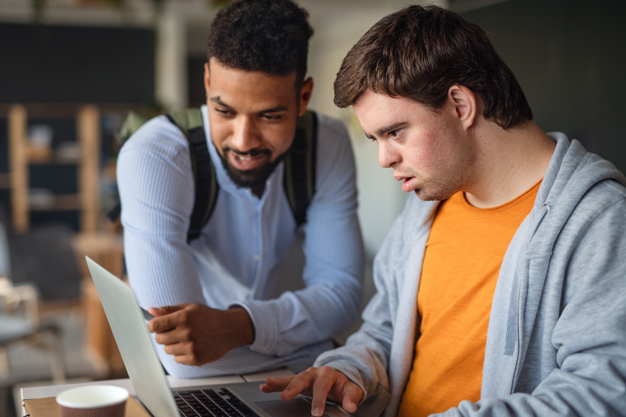 A support coordinator assisting a young man with a disability on a laptop, representing expert Melbourne NDIS support coordination by Care Compatible.