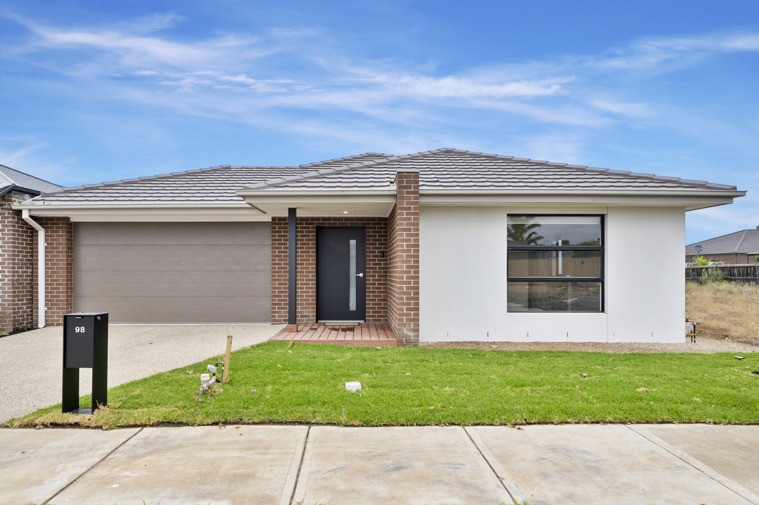 Front view of a modern medium-term accommodation NDIS home in Melbourne, featuring a neat lawn and contemporary architectural design.