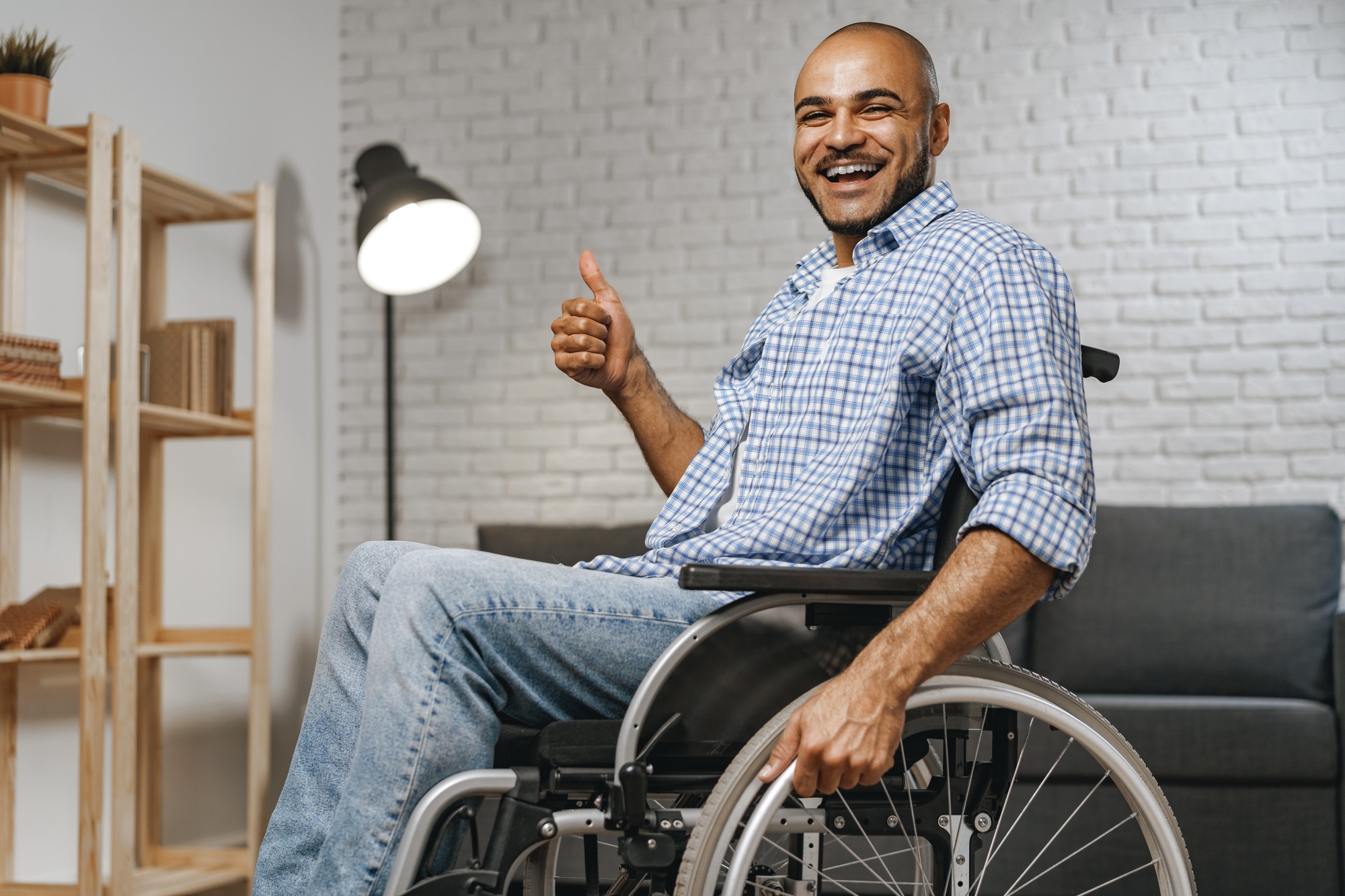 Happy man in a wheelchair giving a thumbs-up, symbolizing independence and quality support in NDIS accommodation services.