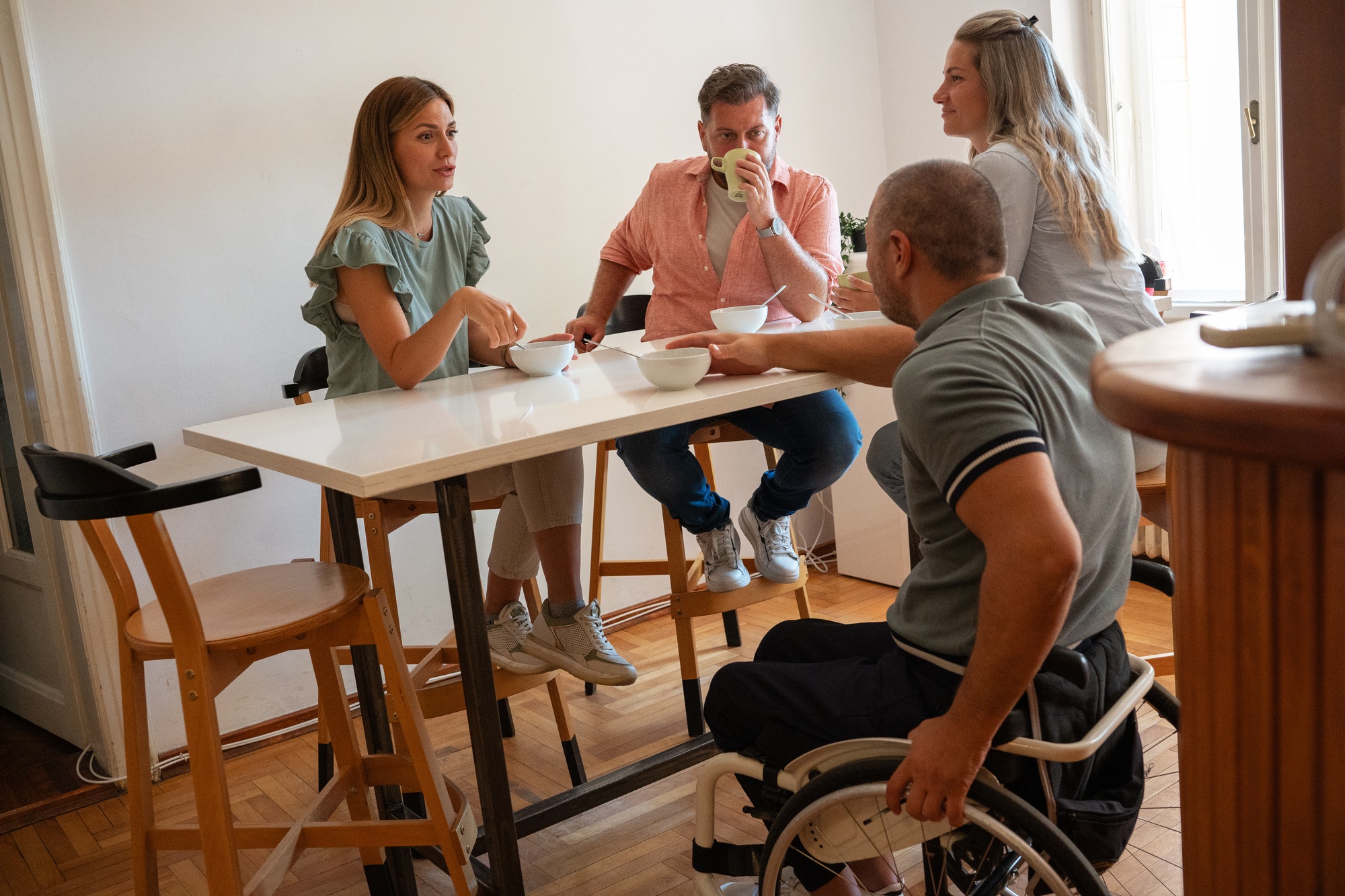 Group of people, including a wheelchair user, enjoying a meal together, representing Supported Independent Living in Melbourne.