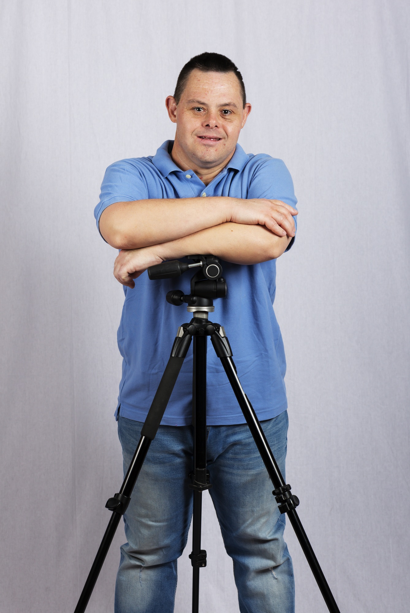 Man with Down syndrome smiling confidently with a tripod, symbolizing independence through NDIS Capacity Building support.