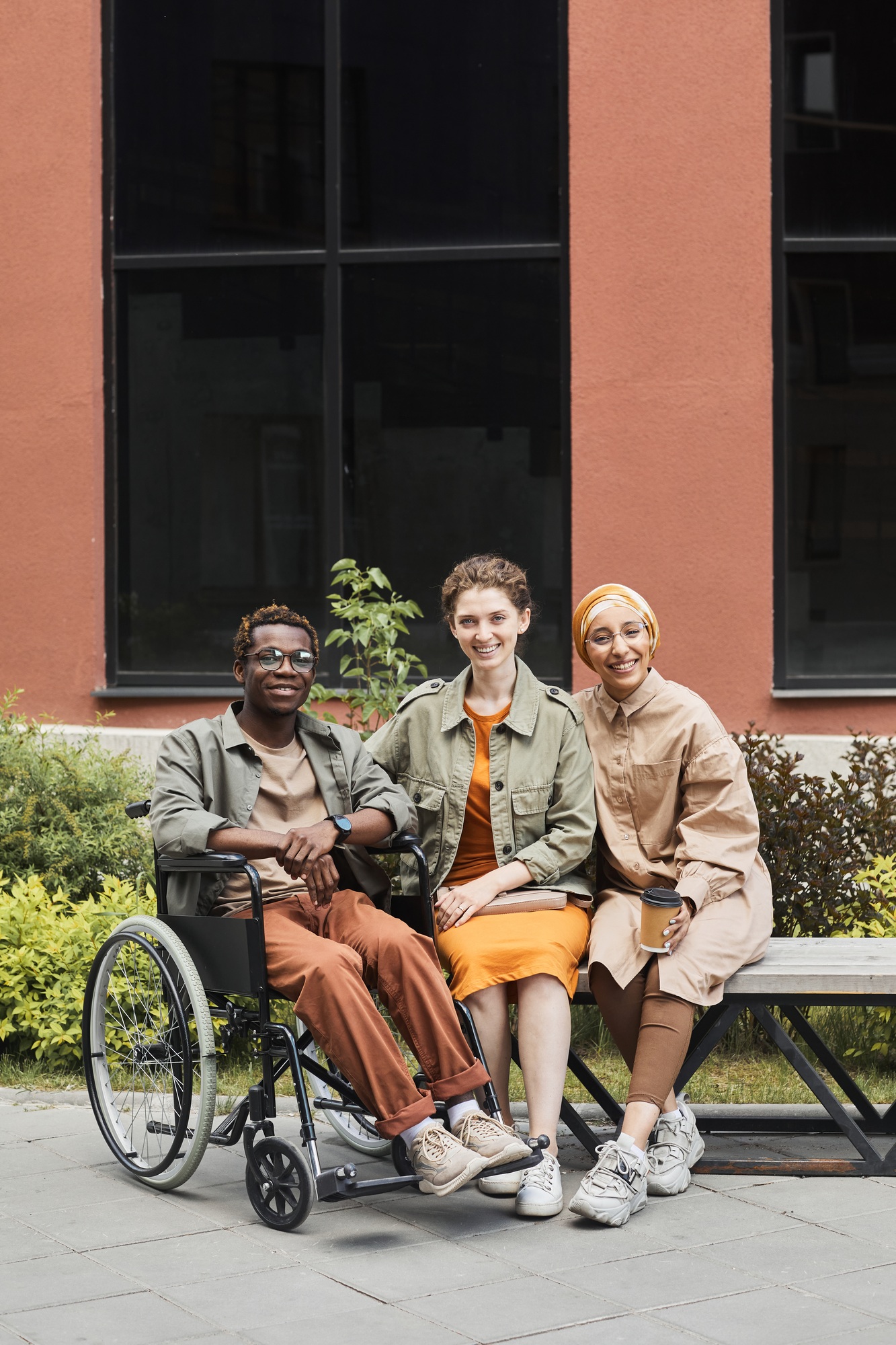 Diverse group including a wheelchair user sitting together outdoors, representing NDIS Capacity Building in the community.