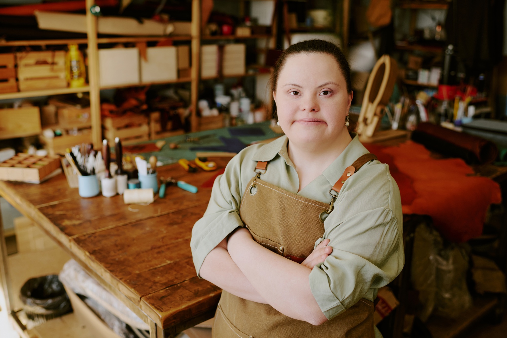 Young woman with Down syndrome confidently standing in a workshop, representing empowerment through NDIS skill development and personalised employment support.