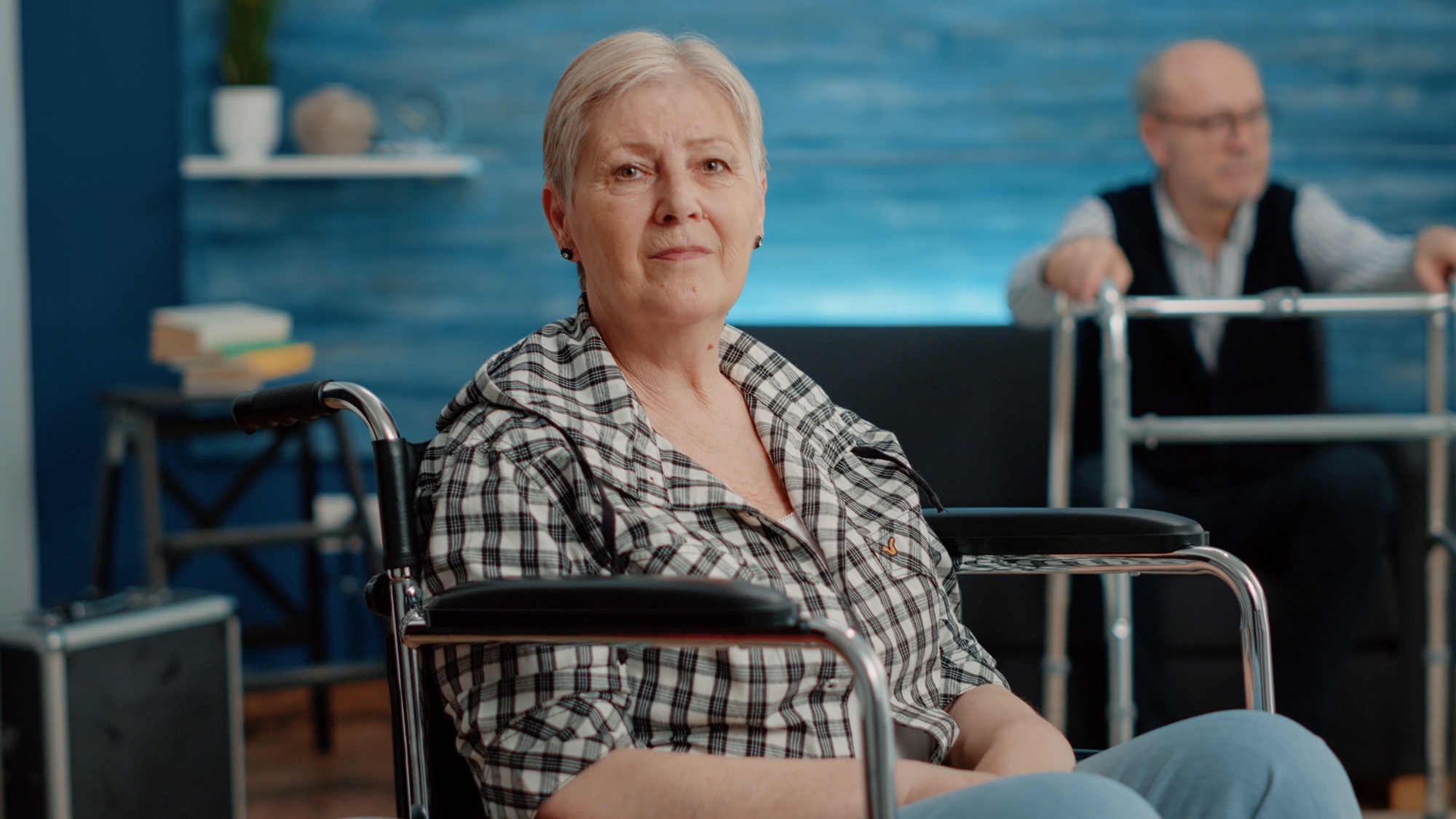 Older woman in a wheelchair with caregiver in the background, representing independence through NDIS Capacity Building support.