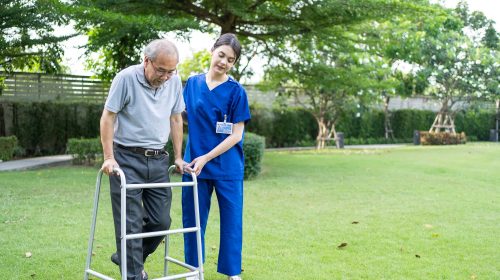 A professional caregiver offering nursing care to an elderly person outdoors.